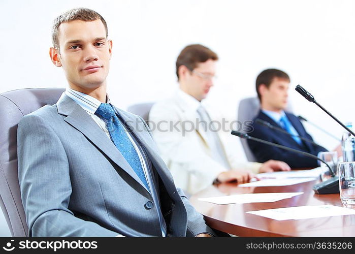 Image of three businesspeople at table at conference