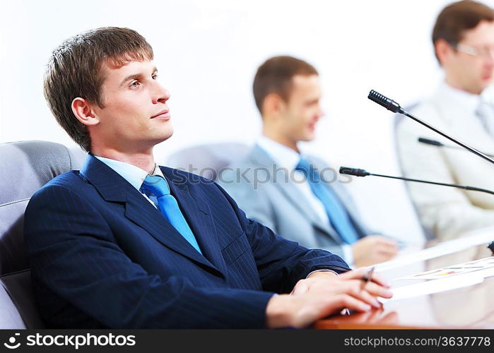 Image of three businesspeople at table at conference