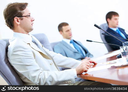 Image of three businesspeople at table at conference