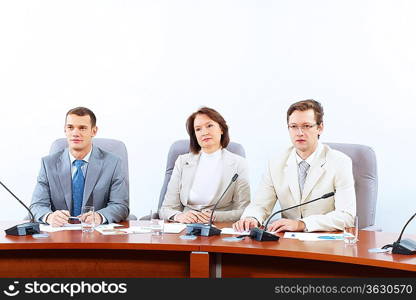 Image of three businesspeople sitting at table at conference