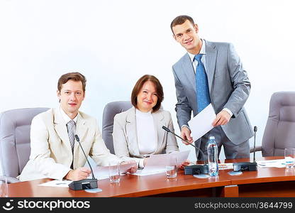 Image of three businesspeople sitting at table at conference