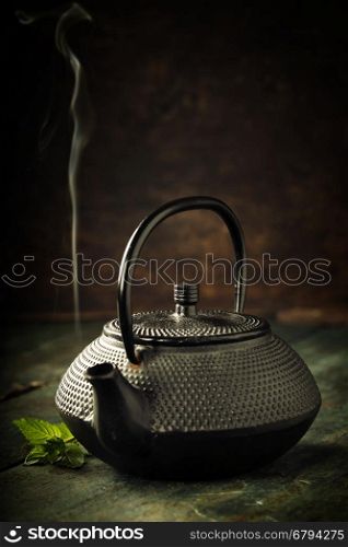Image of traditional eastern teapot on wooden desk