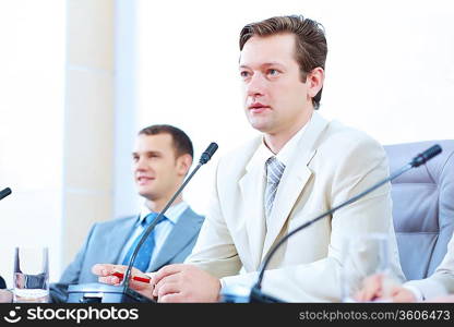 Image of two businessmen sitting at table at conference