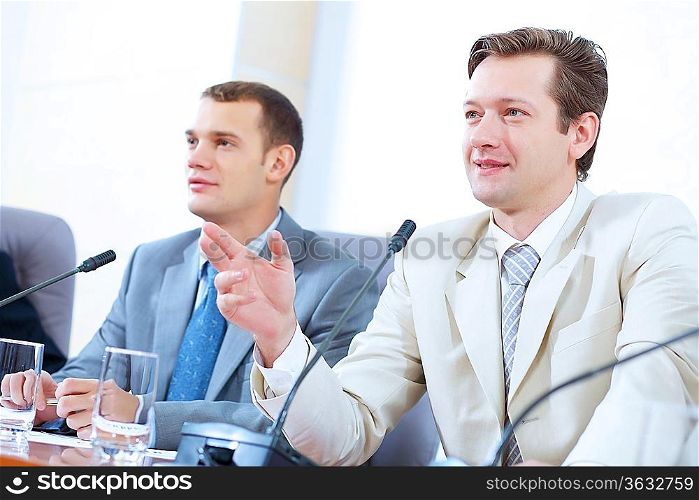 Image of two businessmen sitting at table at conference