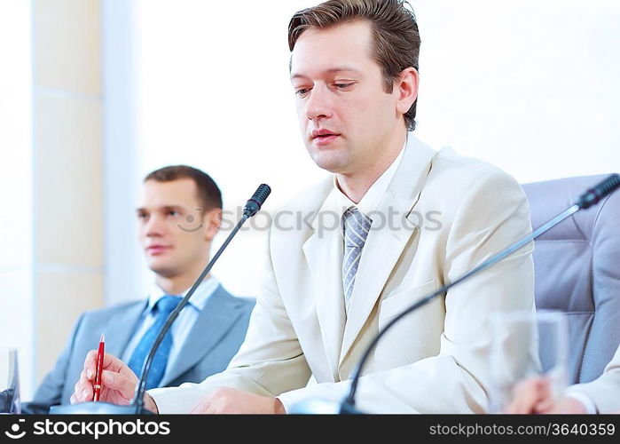 Image of two businessmen sitting at table at conference