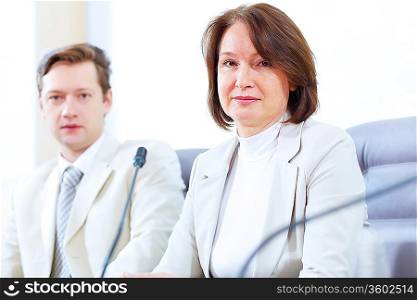 Image of two businesspeople sitting at table at conference
