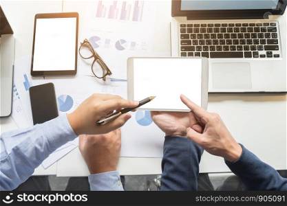 Image of two young businessmen working with laptop, tablet, smartphone and financial document data graph on table in office.