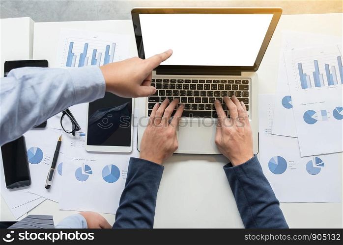 Image of two young businessmen working with laptop, tablet, smartphone and financial document data graph on table in office.