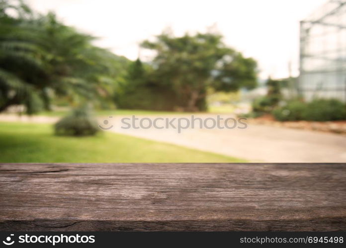 Image of wooden table in front of abstract blurred background of outdoor garden lights. can be used for display or montage your products.Mock up for display of product.