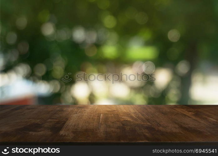 Image of wooden table in front of abstract blurred background of outdoor garden lights. can be used for display or montage your products.Mock up for display of product.