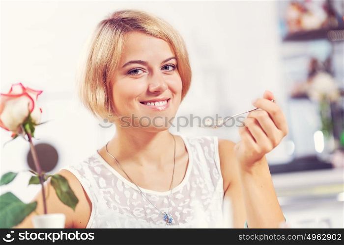 Image of young and pretty woman having dessert in cafe. This is super delicious