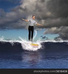 Image of young business person surfing on the waves of the ocean