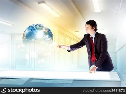 Image of young businessman clicking icon on high-tech picture of globe