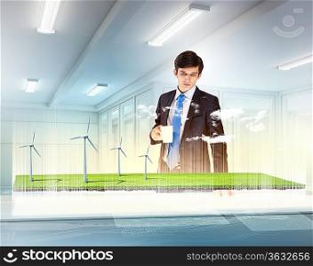 Image of young businessman looking at high-tech picture of windmills