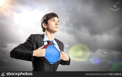 Image of young businessman showing superhero suit underneath his shirt