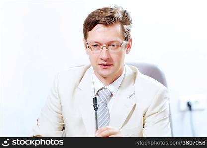 Image of young businessman sitting at table at business meeting