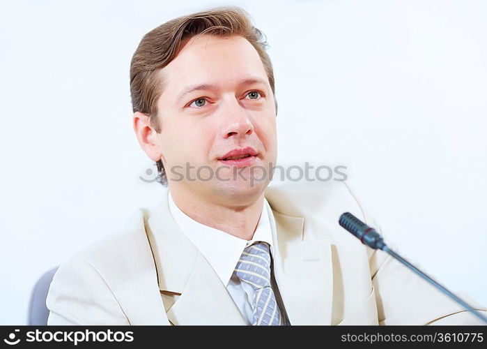 Image of young businessman sitting at table at business meeting