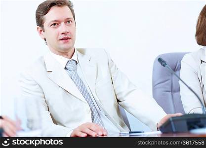 Image of young businessman sitting at table at business meeting