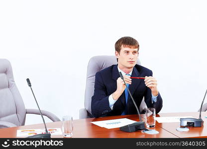 Image of young businessman sitting at table at business meeting