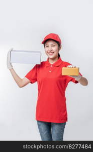 Image of  young delivery man in red cap blank t-shirt uniform standing with empty white cardboard box isolated on light gray background studio