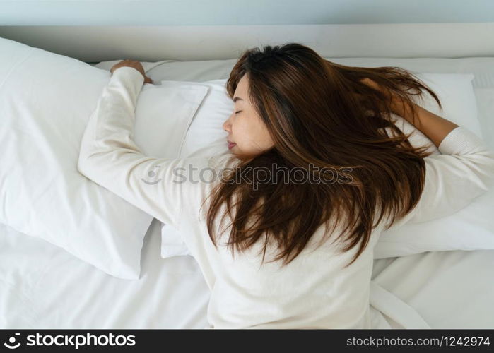 Image of young pretty lady lies in bed indoors. Eyes closed.