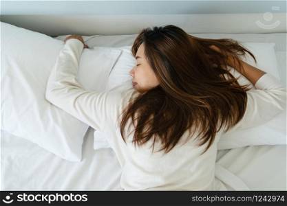 Image of young pretty lady lies in bed indoors. Eyes closed.