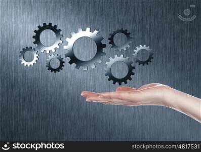 Image with machinery gears and human hand