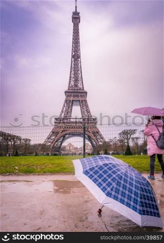 Image with the Eiffel tower and an umbrella in foreground on a rainy day of February, in Paris, France.