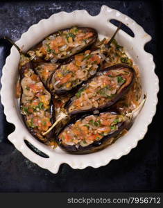 Imam Bayildi. Eggplants stuffed with vegetables in a baking tray. Turkish food. Top view. . Imam Bayildi. Eggplants stuffed with vegetables