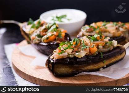 Imam Bayildi. Eggplants stuffed with vegetables on wooden board. Turkish food, closeup, selective focus