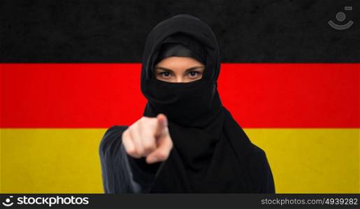 immigration and people concept - muslim woman in hijab pointing finger to you over german flag background. muslim woman in hijab pointing finger to you