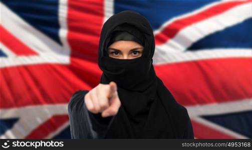 immigration and people concept - muslim woman in hijab pointing finger to you over british flag background. businesswoman or saleswoman giving car key