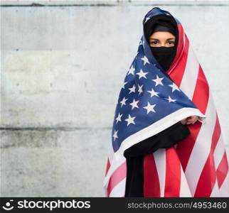 immigration and people concept - muslim woman in hijab with american flag over gray concrete wall background. muslim woman in hijab with american flag