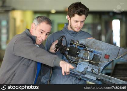 impatient man pointing where apprentice needs to direct machine