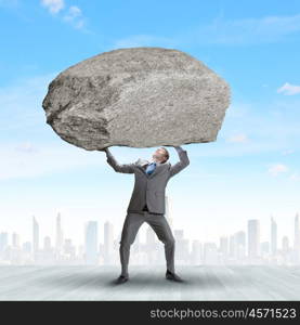 Impending problems. Powerful businessman holding huge stone above head