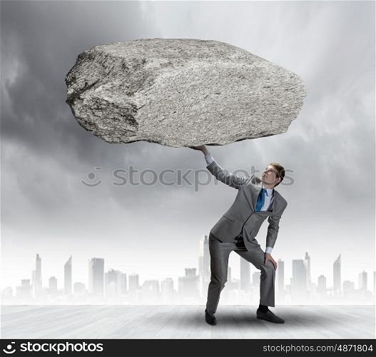 Impending problems. Powerful businessman holding huge stone above head
