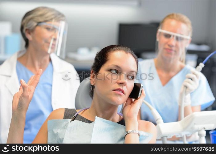 Impolite businesswoman on phone in dental office letting dentist wait