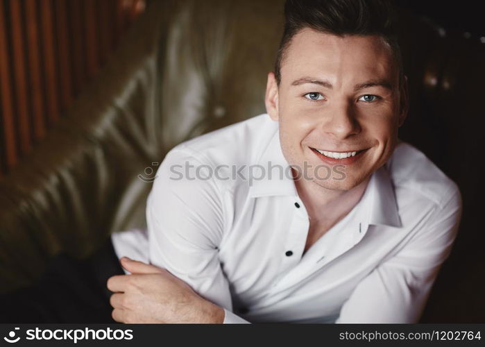 Imposing well dressed in suit man in a luxurious apartments with classic wooden interior. Luxury. Men&rsquo;s beauty, fashion. Sexy groom in tuxedo and bow tie, posing in wedding morning.