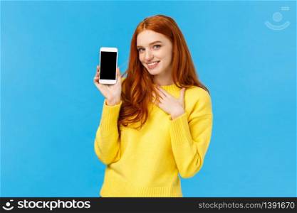 Impressed and fascinated redhead sassy woman touch heart and flirty gazing camera showing sexy guy photo she met dating app, holding smartphone with display facing camera, blue background.. Impressed and fascinated redhead sassy woman touch heart and flirty gazing camera showing sexy guy photo she met dating app, holding smartphone with display facing camera, blue background