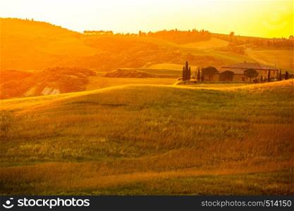 Impressive view of hilly Tuscany in the golden light of sunset with the cultivated land, the typical Italian house and meadow of grass in Valdorcia, Italy