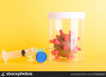 Imprison prevent plasticine disease cells virus in bottle, vaccine and syringe for research in lab of coronavirus outbreak and coronaviruses influenza flu, isolated on yellow, COVID-19 medical concept