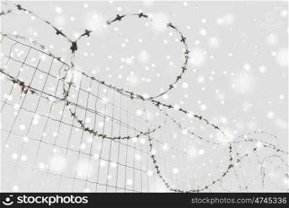imprisonment and restriction concept - barb wire fence over gray sky and snow. barb wire fence over gray sky and snow