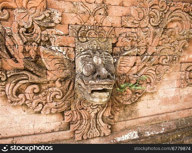In a Hindu temple on Bali, a god&rsquo;s face is designed into a highly decorated red brick wall