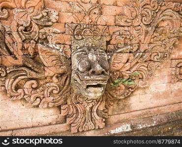 In a Hindu temple on Bali, a god&rsquo;s face is designed into a highly decorated red brick wall