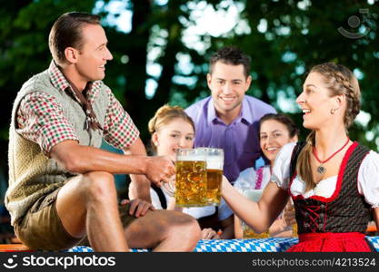 In Beer garden - friends in Lederhosen drinking a fresh beer in Bavaria, Germany