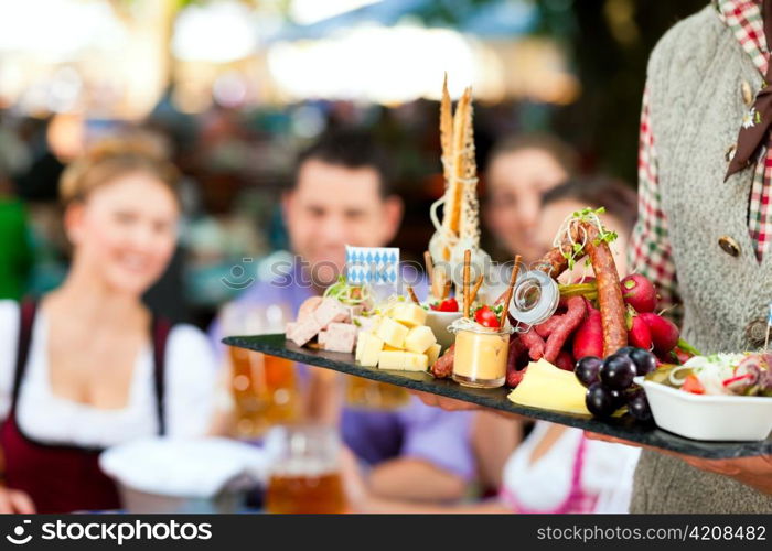 In Beer garden - friends Tracht, Dirndl and on a table with beer and snacks in Bavaria, Germany