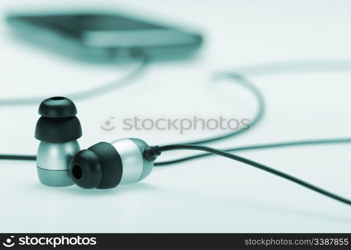 in ear headphone with mobile audio player on bokeh background. Blue toned