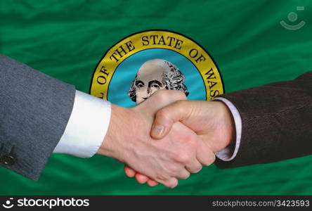 in front of american state flag of washington two businessmen handshake after good deal