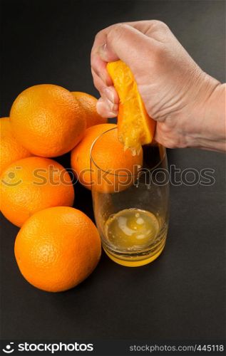 in hand manual juicer with oranges on dark background