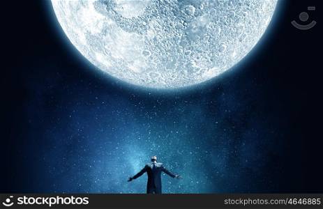 In light of moon. Businessman with hands spread apart looking at moon above